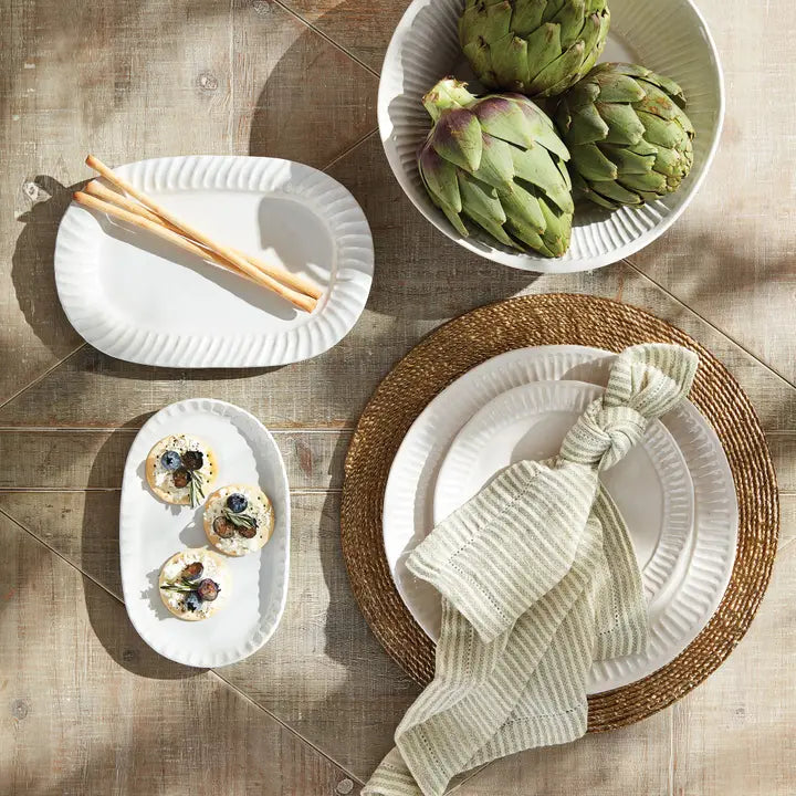 Dining table setting with plates, artichokes, and bread topped with herbs. | SW Home