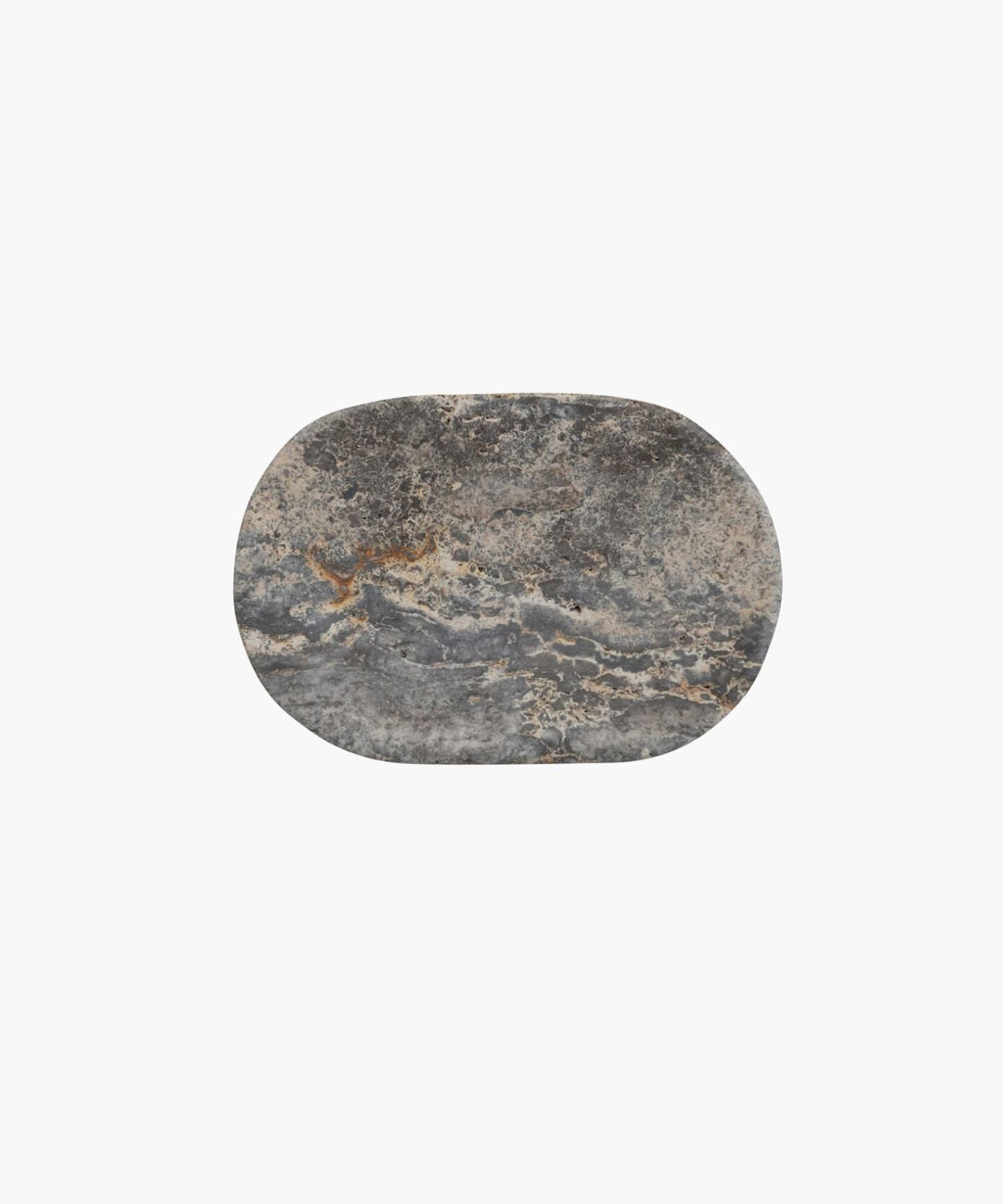 Overhead view of an oval shaped travertine soap dish with a rough, textured surface in shades of gray and hints of brown. It conveys a rustic, natural, and minimalist aesthetic.